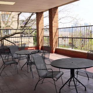 A serene outdoor seating area featuring several tables and chairs, ideal for enjoying the sunshine and a peaceful view.