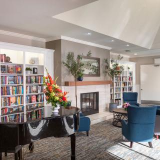 A cozy living room with a piano, bookshelves, and a fireplace.