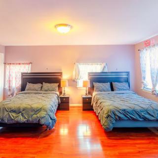 A bright bedroom with two neatly made beds and hardwood flooring.