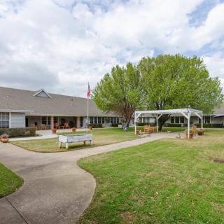A serene courtyard with a central pathway, surrounded by a building and greenery.