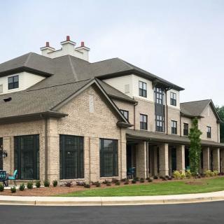 A three-story residential building with brick exterior and a well-maintained lawn.