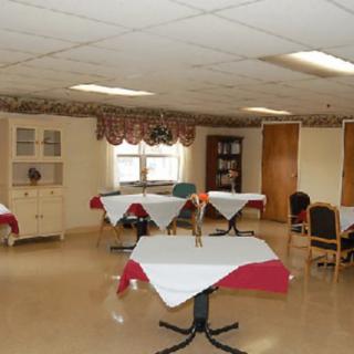 A cozy dining room with neatly arranged tables and chairs, featuring red and white tablecloths.