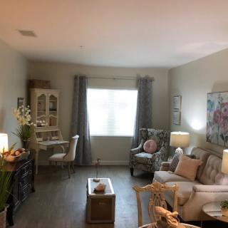 A cozy living room with elegant furniture and decor, featuring a window allowing natural light to brighten the space.