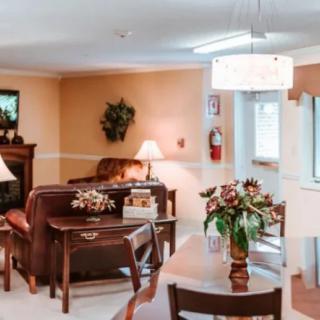 A cozy living room featuring a sofa, table with flowers, and a fireplace.