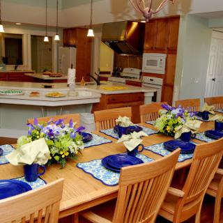 A beautifully arranged dining area in a modern kitchen, featuring a wooden table with floral centerpieces and blue plates.