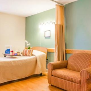 A well-furnished hospital room with a patient bed and comfortable seating.