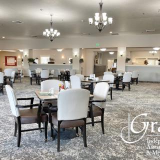 An elegant dining area with neatly arranged tables and chairs, illuminated by chandeliers.