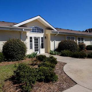 A residential house with landscaped shrubs and a clear blue sky.