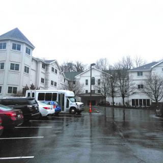 A view of a multi-story residential building with a parking lot under an overcast sky.