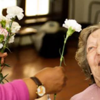 An elderly person receiving flowers with a joyful expression.