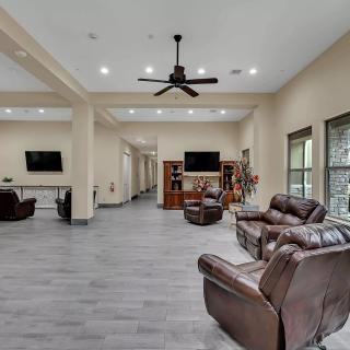 A spacious and modern living room with leather sofas, a television, and ceiling fans.