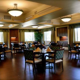 A cozy dining room with neatly arranged tables and chairs, featuring warm lighting.