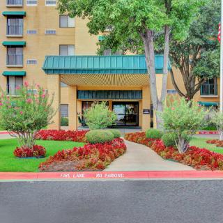 The entrance of a hotel with well-maintained landscaping and a clear pathway leading to the door.