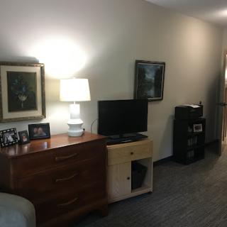 A cozy living room setup featuring a television, lamp, and wall art.
