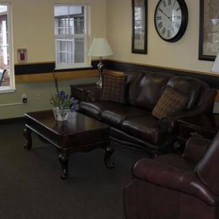 A cozy living room with a leather sofa, coffee table, and decorative clock on the wall.