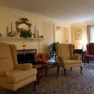 A cozy living room with traditional armchairs and a fireplace, decorated with classic accents.