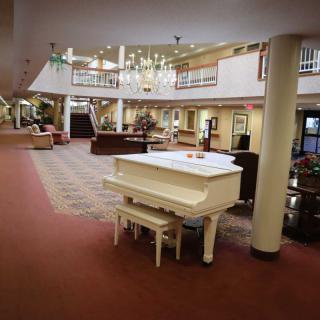A spacious lobby interior featuring a white piano and seating areas.