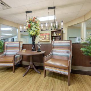 A cozy waiting area with two chairs and a table adorned with a flower arrangement.