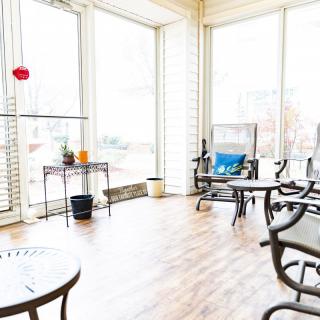 A bright sunroom filled with natural light, featuring comfortable chairs and a table.