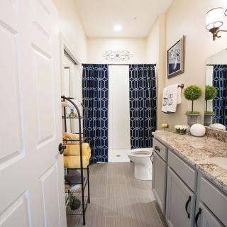 A well-decorated bathroom with a granite countertop, blue shower curtain, and elegant lighting.