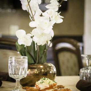 A beautifully set dining table featuring a flower vase with white blooms and elegant dishware.