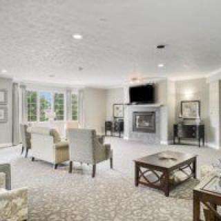 A spacious and elegantly decorated living room featuring a fireplace and television, with comfortable seating arrangements and a central coffee table.