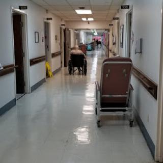 A view of a hospital hallway, featuring a wheelchair and patient transport equipment.