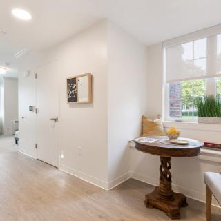 A bright and airy hallway with a cozy window seat and a small wooden table.
