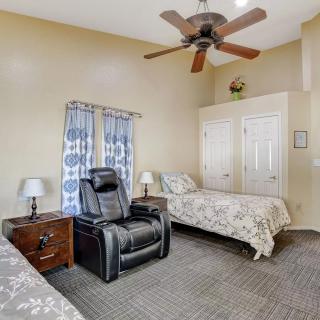 A cozy bedroom with twin beds, a recliner chair, and a ceiling fan.