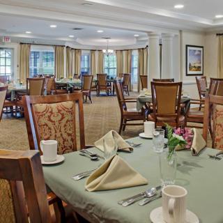 A well-appointed dining room with neatly arranged tables and chairs, featuring elegant table settings.