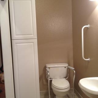 An accessible bathroom with a grab bar and a cabinet.