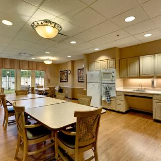 A spacious kitchen and dining area featuring a long table with chairs, cabinets, and appliances.