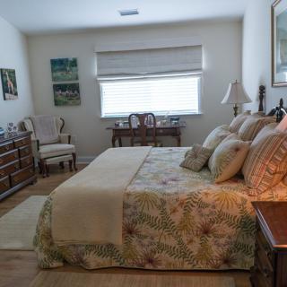 A cozy bedroom with a neatly arranged bed, decorative pillows, and classic furniture.
