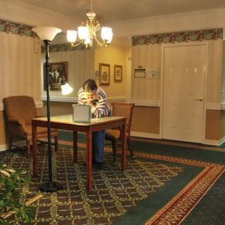 A person sits at a desk reading in a warmly lit room.