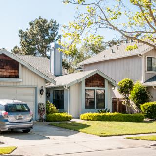A suburban house with a driveway, car, and well-maintained yard on a sunny day.