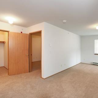 An empty bedroom with carpet flooring, a closet, and a window.