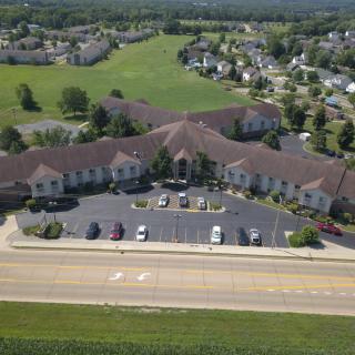 Aerial view of a large building with a parking lot, surrounded by a residential neighborhood and greenery.