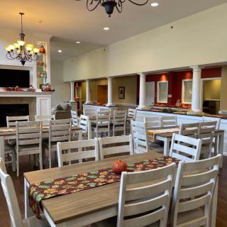 A cozy dining area with wooden tables and chairs, featuring a chandelier and warm decor.