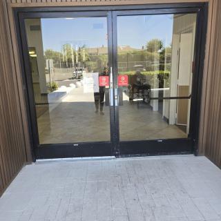 A glass entrance with automatic sliding doors reflecting the outdoor scenery.