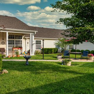 A serene backyard with a patio, lush green lawn, and outdoor seating area.