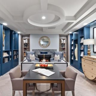 A luxurious home office with modern blue walls, elegant furniture, and built-in bookshelves.