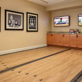 Art gallery room with framed pictures, wooden flooring, and wall-mounted televisions.
