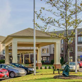 Exterior view of a hotel entrance with a parking lot and cars.