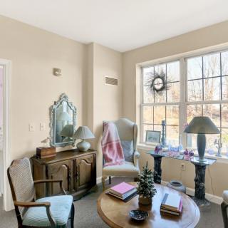A cozy living room with elegant furniture and a large window allowing natural light to stream in.