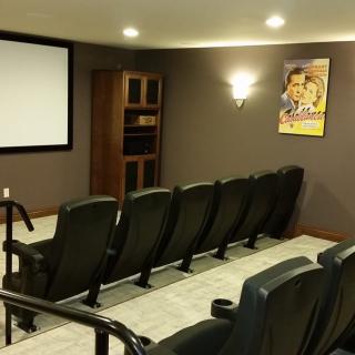 A cozy home theater with tiered seating and a large screen, perfect for movie nights.