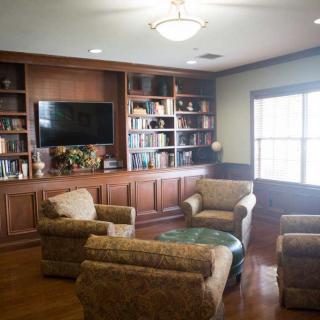 A cozy living room with bookshelves, armchairs, and a television.