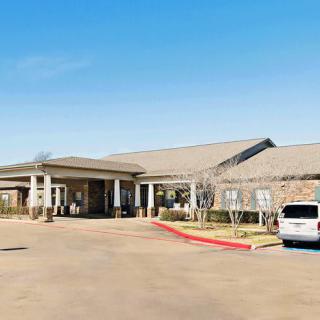 A single-story building with a parking lot and a car under a clear blue sky.