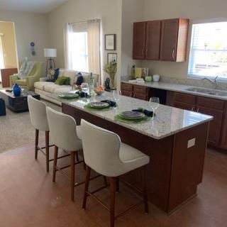 Modern open-concept kitchen with an island and bar stools, adjacent to the living room.