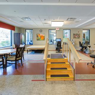 A spacious rehabilitation facility equipped with exercise equipment and a small set of stairs for physical therapy exercises.