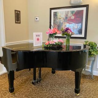 A grand piano decorated with flowers in an elegant room setting.
